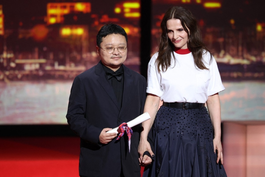 Đạo diễn Trung Quốc Bi Gan (trái) nhận giải đặc biệt từ chủ tịch ban giám khảo Juliette Binoche trong lễ bế mạc Liên hoan phim Cannes lần 78. Ảnh: AFP