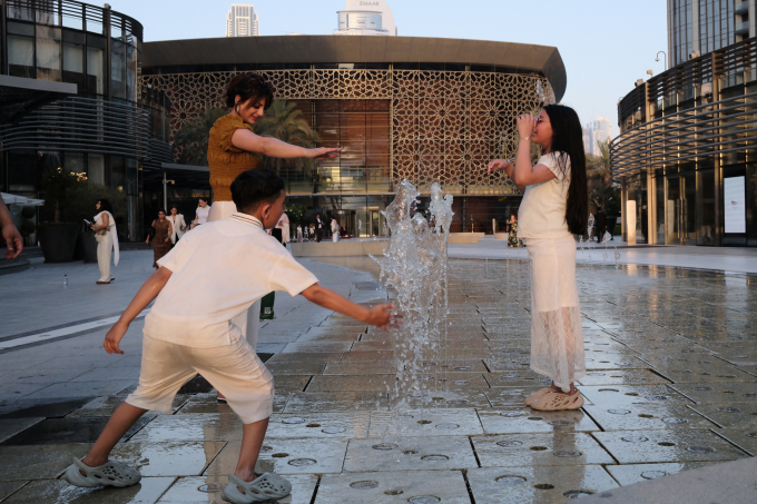 Người dân Dubai giải nhiệt bên cột phun nước ngày 24/5. Ảnh: AFP