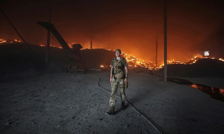 Binh sĩ Ukraine trước một kho hạt giống bị bốc cháy vì pháo kích ở Donetsk, Ukraine, ngày 31/5. Ảnh: Reuters.