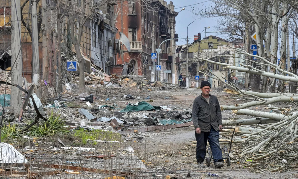 Người đàn ông đi qua con phố với những ngôi nhà bị hư hại trong giao tranh tại thành phố Mariupol, miền nam Ukraine ngày 8/4. Ảnh: RIA Novosti.