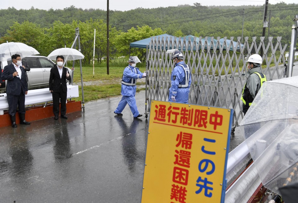Giới chức địa phương dỡ rào chắn một khu vực ở làng Katsurao, tỉnh Fukushima, đông bắc Nhật Bản, hôm 12/6. Ảnh: Kyodo.