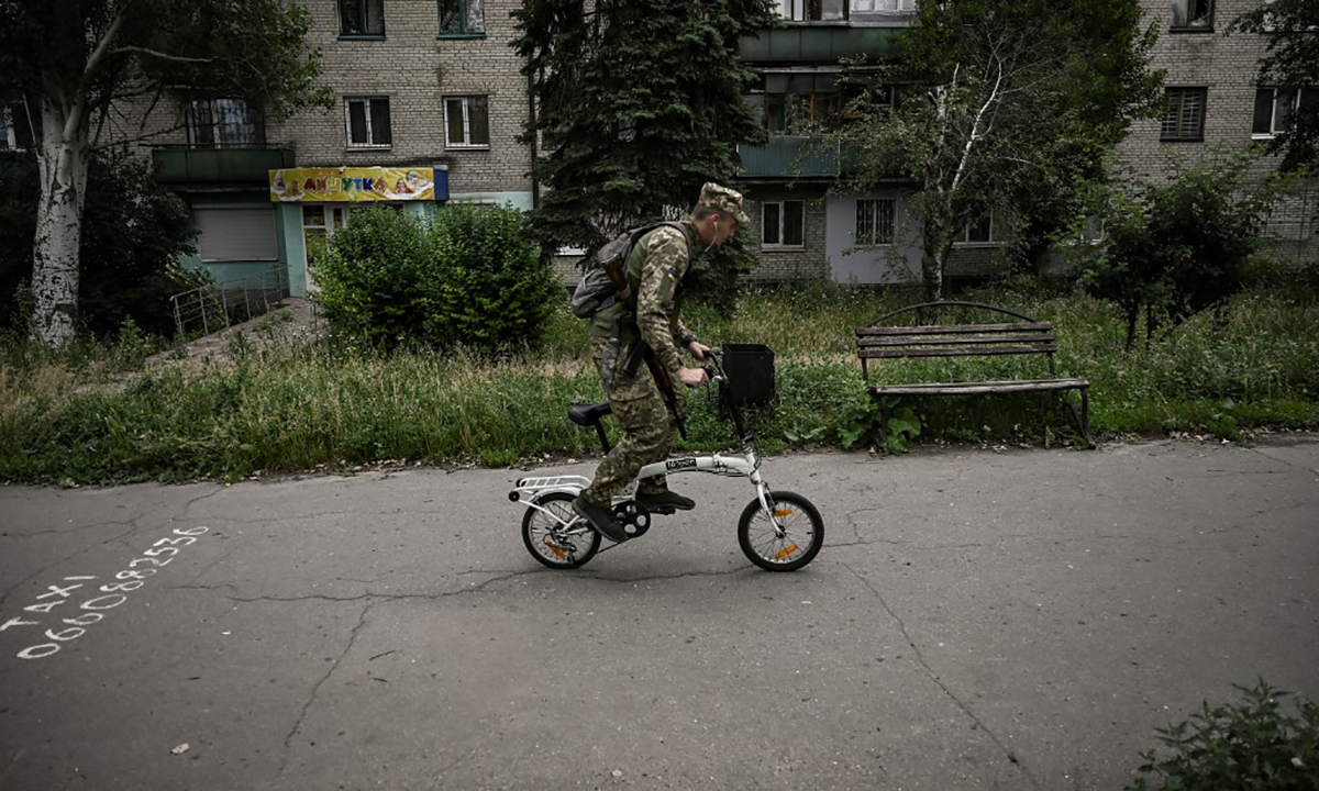 Một binh sĩ Ukraine đạp xe trên đường phố Lysychansk ngày 18/6. Ảnh: AFP.