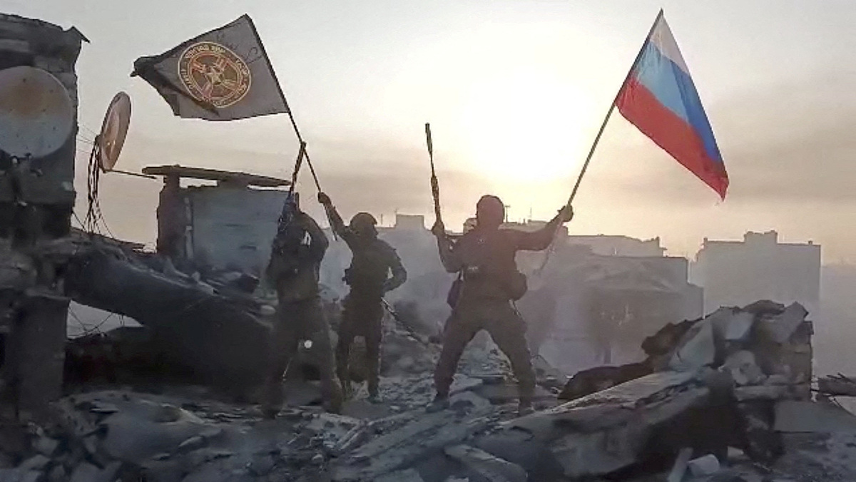 Thành viên lực lượng Wagner giương cờ Nga và cờ Wagner trên tòa nhà đổ nát không rõ địa điểm trong video công bố ngày 20/5. Ảnh: Reuters