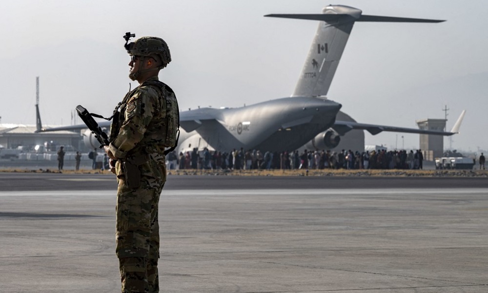 Lính Mỹ đứng gác tại sân bay Kabul, Afghanistan hôm 20/8/2021, phía xa là đoàn người đang xếp hàng lên vận tải cơ quân sự C-17. Ảnh: AFP