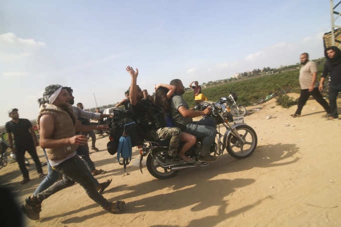 Thành viên Hamas đưa người phụ nữ Israel (ngồi giữa) bị bắt làm con tin từ khu định cư Kfar Azza của Israel tới Dải Gaza hôm 7/10. Ảnh: AP