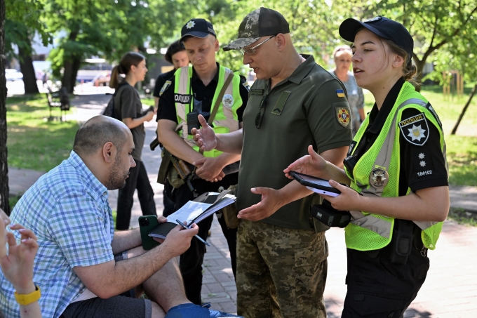 Quân nhân và cảnh sát Ukraine kiểm tra tại chỗ giấy tờ của đàn ông trong độ tuổi nhập ngũ và đưa giấy triệu tập quân sự ở Kiev ngày 7/6. Ảnh: AFP