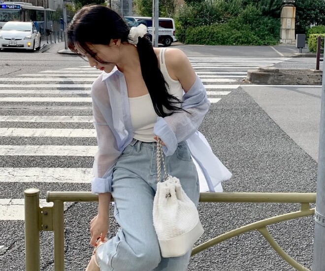 Trẻ trung và hiện đại với áo hai dây ôm sát cùng sơ mi xuyên thấu màu xanh pastel. Quần jean ống rộng tạo sự cân bằng, trong khi phụ kiện trắng như túi vải và scrunchie mang đến vẻ năng động, tinh giản theo phong cách Hàn Quốc.