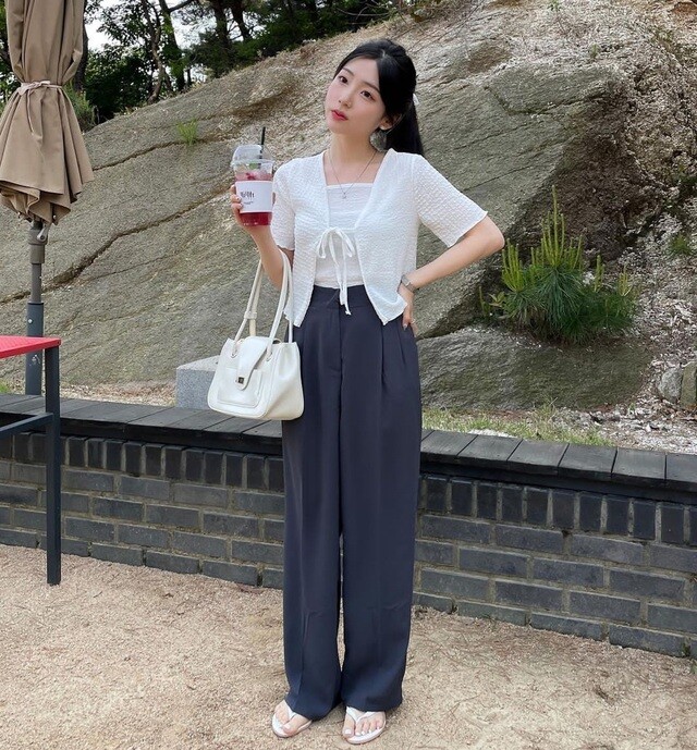 Vẻ đẹp thanh lịch, năng động với áo khoác lửng dệt kim trắng mix cùng áo hai dây ton-sur-ton và quần ống rộng đen.