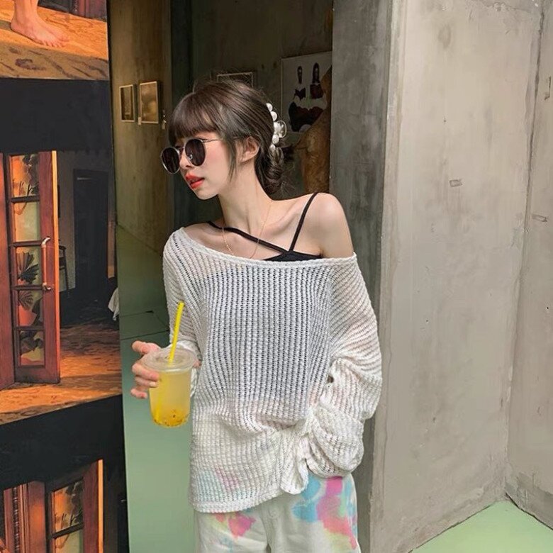 Phá cách và phóng khoáng với áo len dệt mỏng lệch vai, lộ áo 2 dây đen đầy chủ ý. Quần thun loang màu và kính râm tròn cổ điển tạo điểm nhấn thời thượng, lý tưởng cho những buổi café chill mang đậm vibe thành thị nghệ thuật.