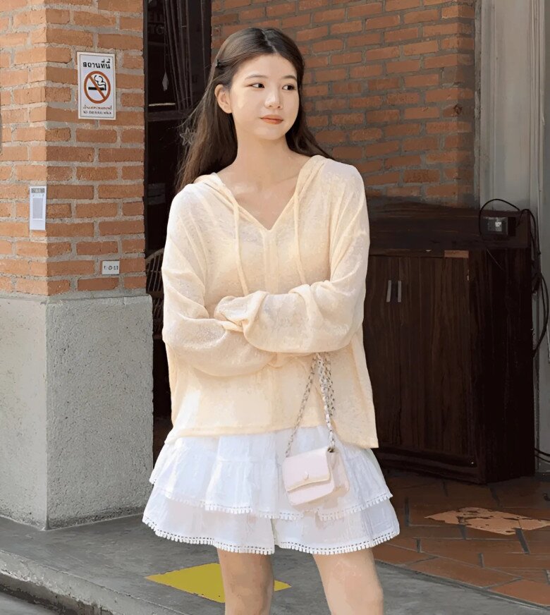 Phong cách “soft girl” ngọt ngào: áo hoodie mỏng màu kem kết hợp váy xếp tầng ren trắng, túi mini hồng pastel – tạo nên tổng thể trong trẻo, nữ tính và cực kỳ hợp với ngày nắng nhẹ.