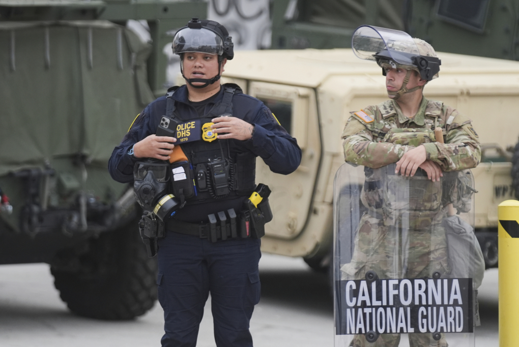 Vệ binh Quốc gia bang California cùng cảnh sát thuộc Bộ An ninh Nội địa Mỹ (DHS) canh gác bên ngoài tòa nhà công vụ liên bang ở Los Angeles ngày 12/6. Ảnh: AP