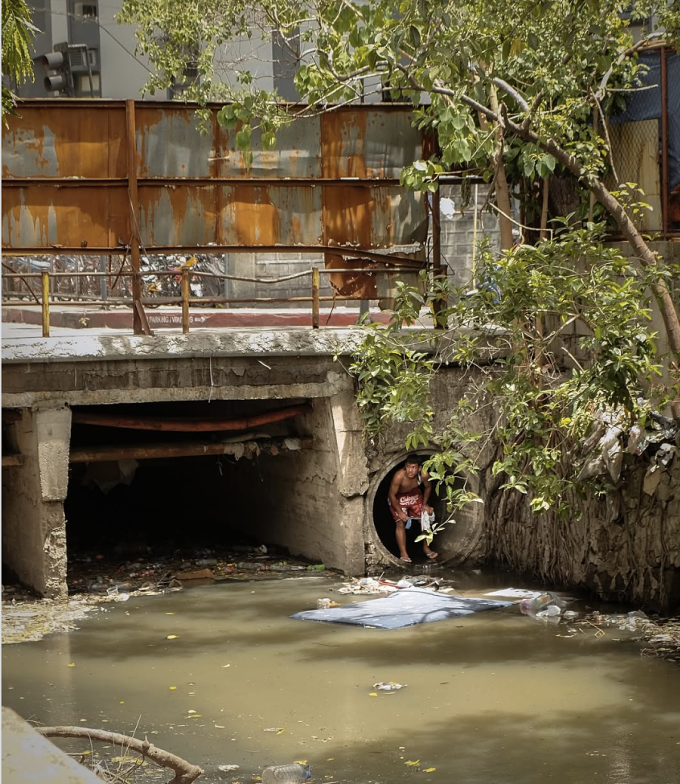 Một người đàn ông chui ra khỏi cống ngầm tại khu vực Trung tâm Y tế Makati, Philippines, cuối tháng 5/2025. Ảnh: William Roberts