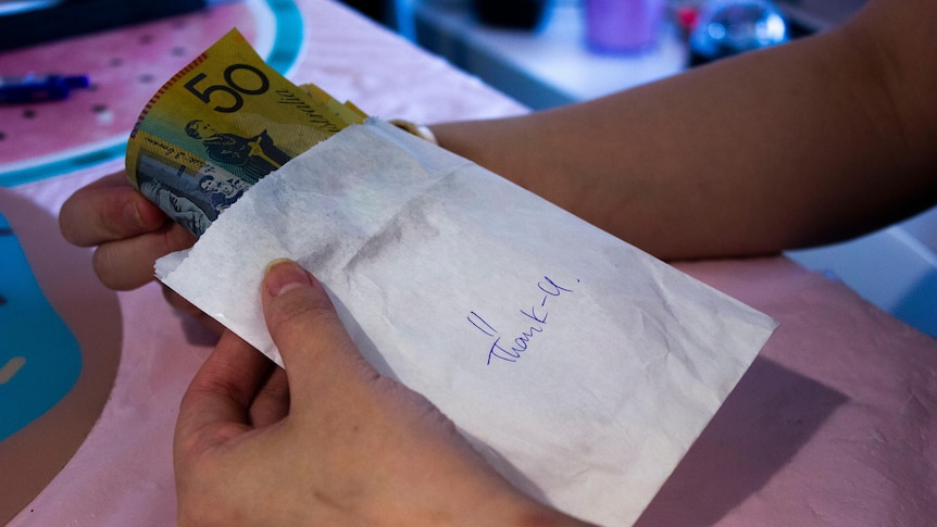Hands holding a cash-filled envelope with 