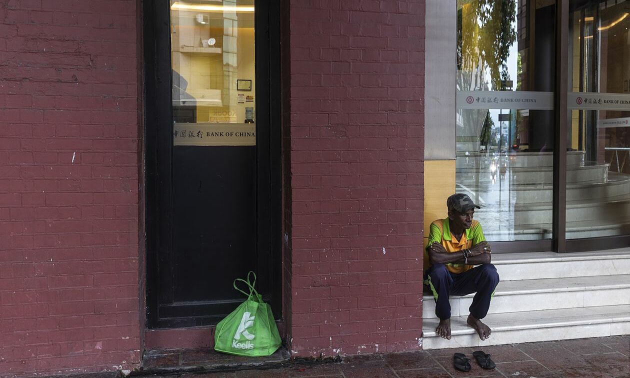 Một người vô gia cư ngồi trước ngân hàng Trung Quốc ở thủ đô Colombo, Sri Lanka. Ảnh: WSJ.