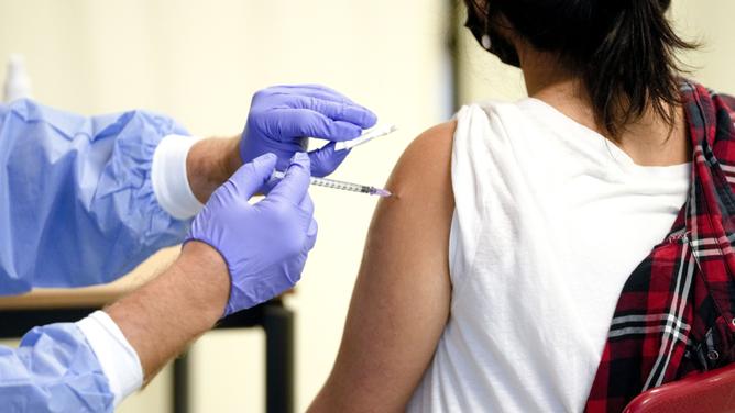 A doctor vaccinates a student with the Moderna COVID-19 vaccine, as part of the vaccination campaign called '#HierWirdGeimpft', #Here We Vaccinate, during a visit of the German President at Ruth Cohn School in Berlin, Germany, Monday, Sept. 13, 2021. German President Frank-Walter Steinmeier visits the school to support the special week-long vaccination campaign which people will be offered the shots without appointments. (AP Photo/Markus Schreiber)