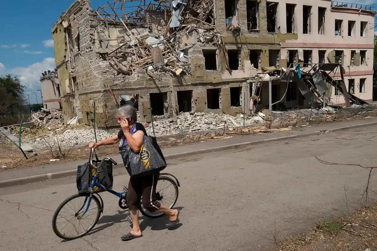 Người phụ nữ đi qua một tòa nhà bị phá hủy vì pháo kích ở Kramatorsk, Ukraine. Ảnh: Guardian.