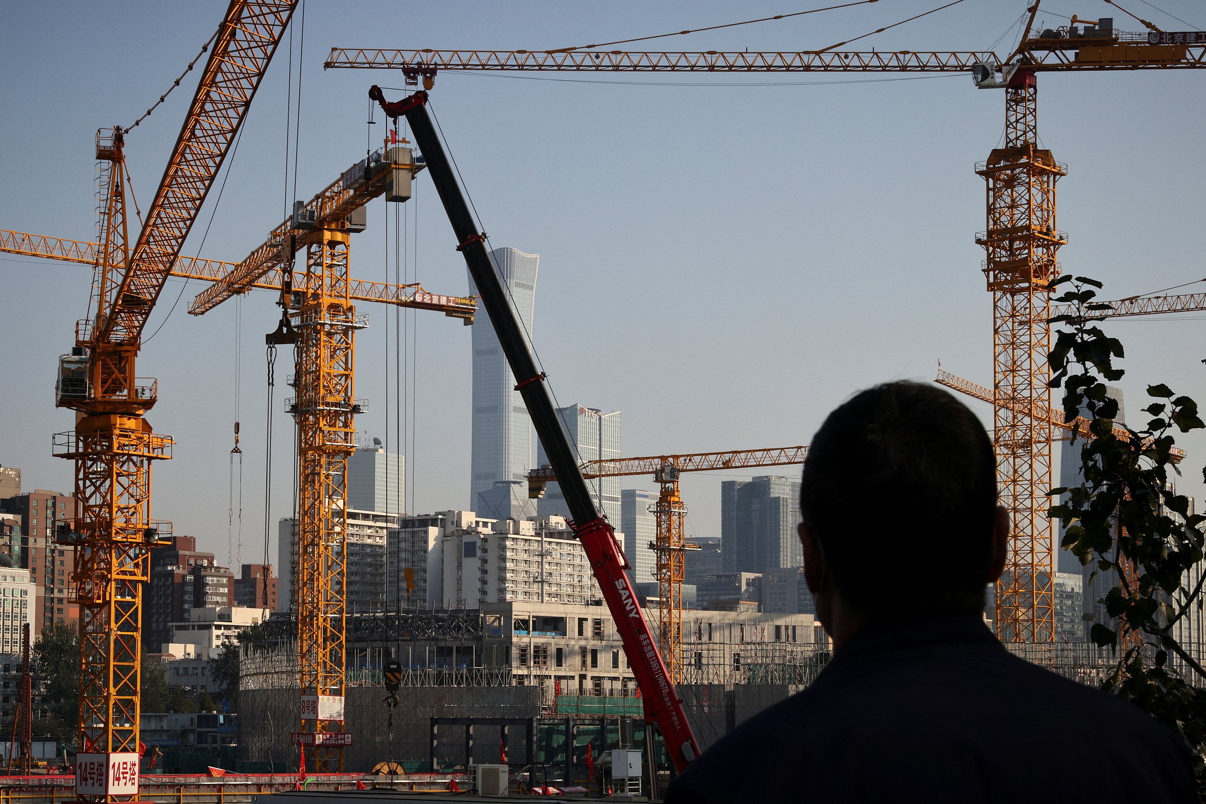 Một người đàn ông nhìn công trình xây dựng ở khu trung tâm Bắc Kinh ngày 18/10/2021. Ảnh: Reuters