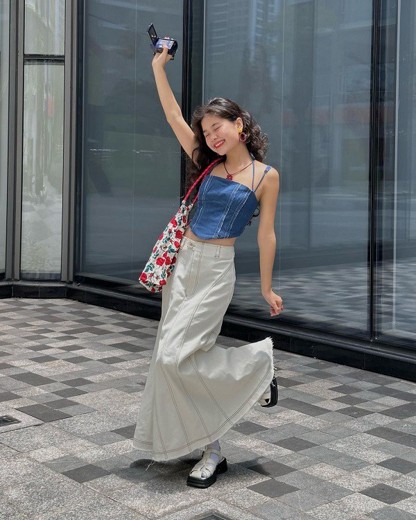 Công thức áo hai dây denim dáng croptop và chân váy maxi mang đến cho người mặc sự năng động, cá tính. Những món phụ kiện như túi đeo vai, dây chuyền tạo điểm nhấn thú vị cho tổng thể. 