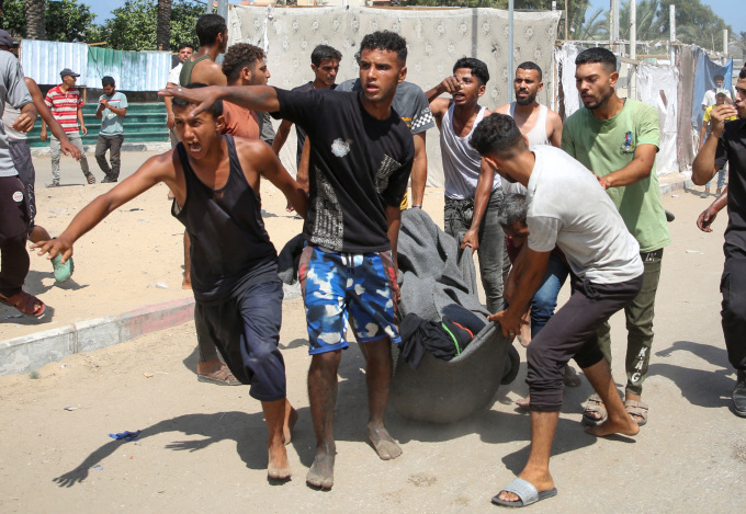 Người dân khiêng nạn nhân trong vụ tập kích lều tị nạn ở Al-Mawasi, Dải Gaza, ngày 13/7. Ảnh: Reuters