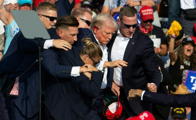 Cựu tổng thống Mỹ Donald Trump với gương mặt đầy máu khi được mật vụ đưa khỏi sân khấu sau vụ ám sát hụt ở Butler, Pennsylvania ngày 13/7. Ảnh: AFP