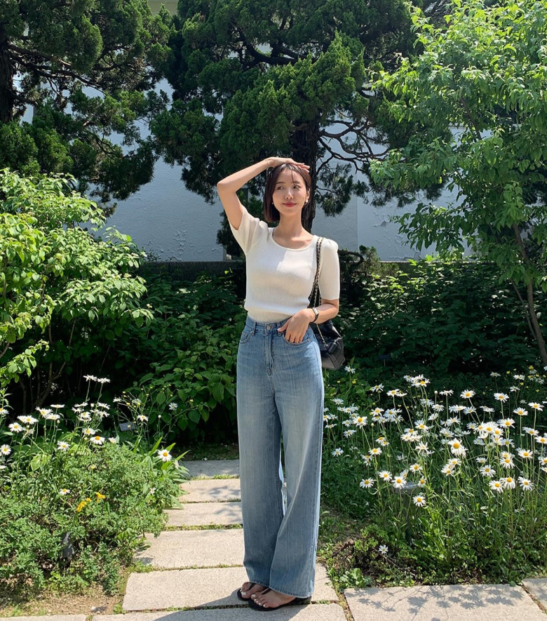 Sự kết hợp tối giản nhưng hiệu quả với áo dệt kim mỏng ôm sát tông trắng kem cùng quần jean ống rộng cạp cao, tạo nên diện mạo nhẹ nhàng, thanh lịch.
