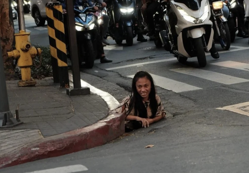 Một phụ nữ được chụp ảnh khi bò ra từ lỗ cống ở Makati, Philippines. Ảnh: William Roberts