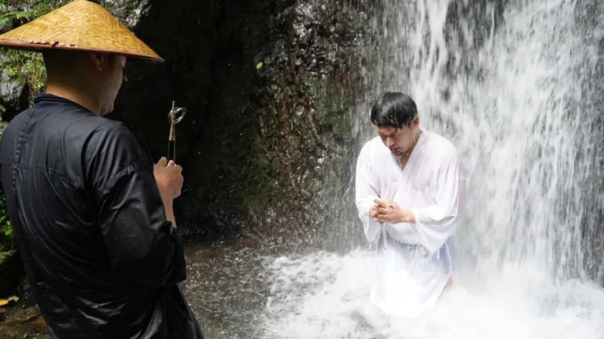 Sư hướng dẫn giám sát trải nghiệm thiền dưới thác của một người tham gia ở chùa Tenko. Ảnh: Zenbird