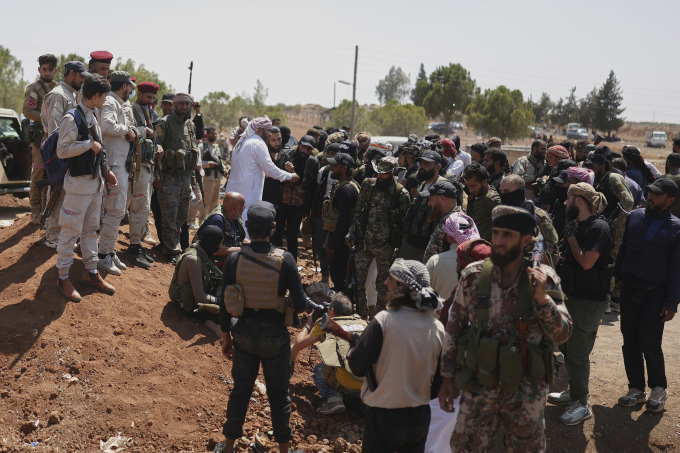 Các chiến binh Bedouin (phải) đứng gác khi bị lực lượng an ninh chính phủ Syria (trái) chặn tiến vào Sweida hôm 20/7. Ảnh: AP