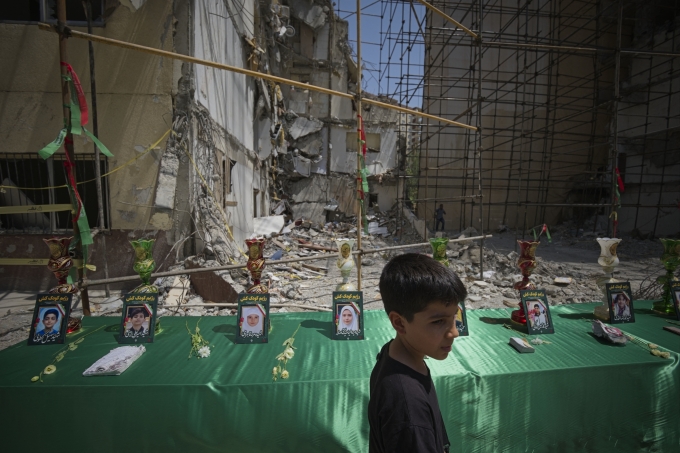 Một cậu bé 10 tuổi ngày 19/7 đi ngang chân dung của các em nhỏ thiệt mạng một vụ không kích của Israel vào khu dân cư ở Tehran trong cuộc chiến 12 ngày. Ảnh: AFP