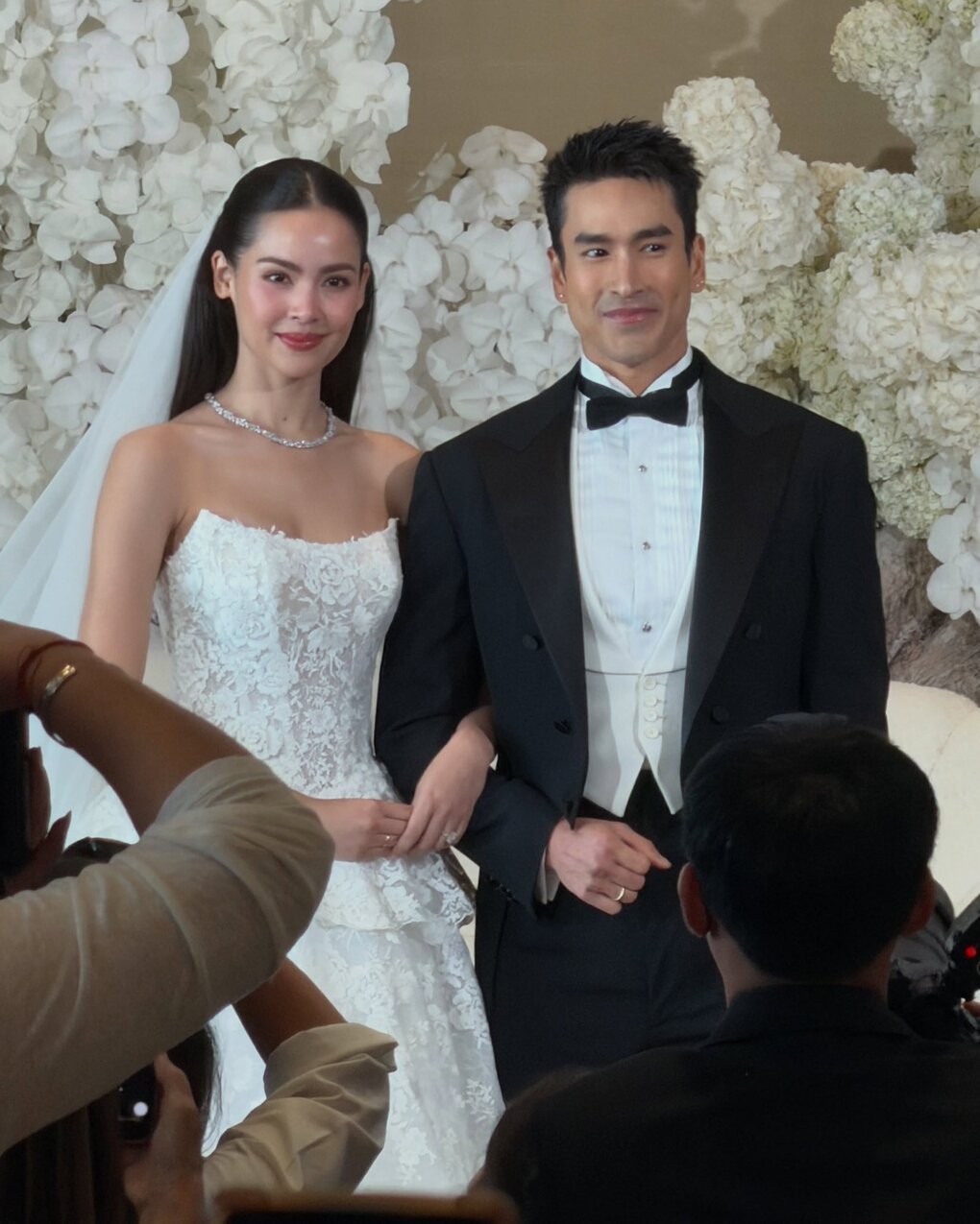 Tại buổi gặp gỡ truyền thông trước giờ cưới chú rể Nadech Kugimiya, cô dâu Yaya-Urassaya Sperbund nhá hàng với một thiết kế thuộc dòng SoL amp; Gravité của Reem Acra. Mẫu váy dạ hội cúp ngực từ bộ sưu tập Roses by Reem Acra gây ấn tượng với chi tiết peplum cùng họa tiết hoa hồng thêu tinh xảo phủ khắp thân váy. Điểm nhấn chính là những lớp ren xếp tầng ở eo, giúp tôn vóc dáng quyến rũ của tân nương.