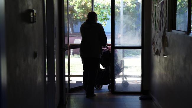 Woman pushes pram at domestic violence shelter.