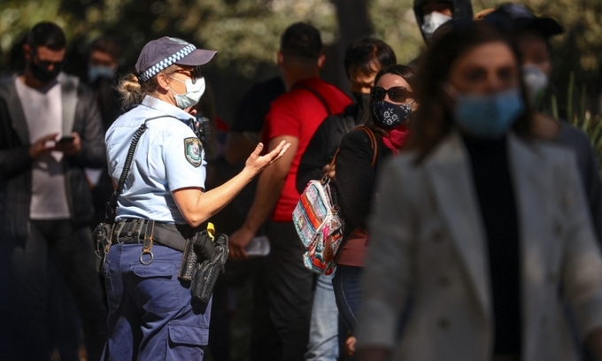 Nữ cảnh sát New South Wales nói chuyện với những người xếp hàng chờ tiêm vaccine Covid-19 tại Sydney hôm 16/8. Ảnh: AFP.