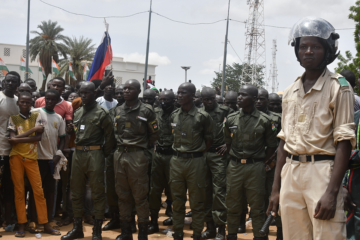 Một cảnh sát Niger đứng cạnh các học viên trường sĩ quan Niger khi những người ủng hộ tập hợp để ủng hộ chính quyền quân sự ở thủ đô Niamey ngày 30/7. Ảnh: AFP