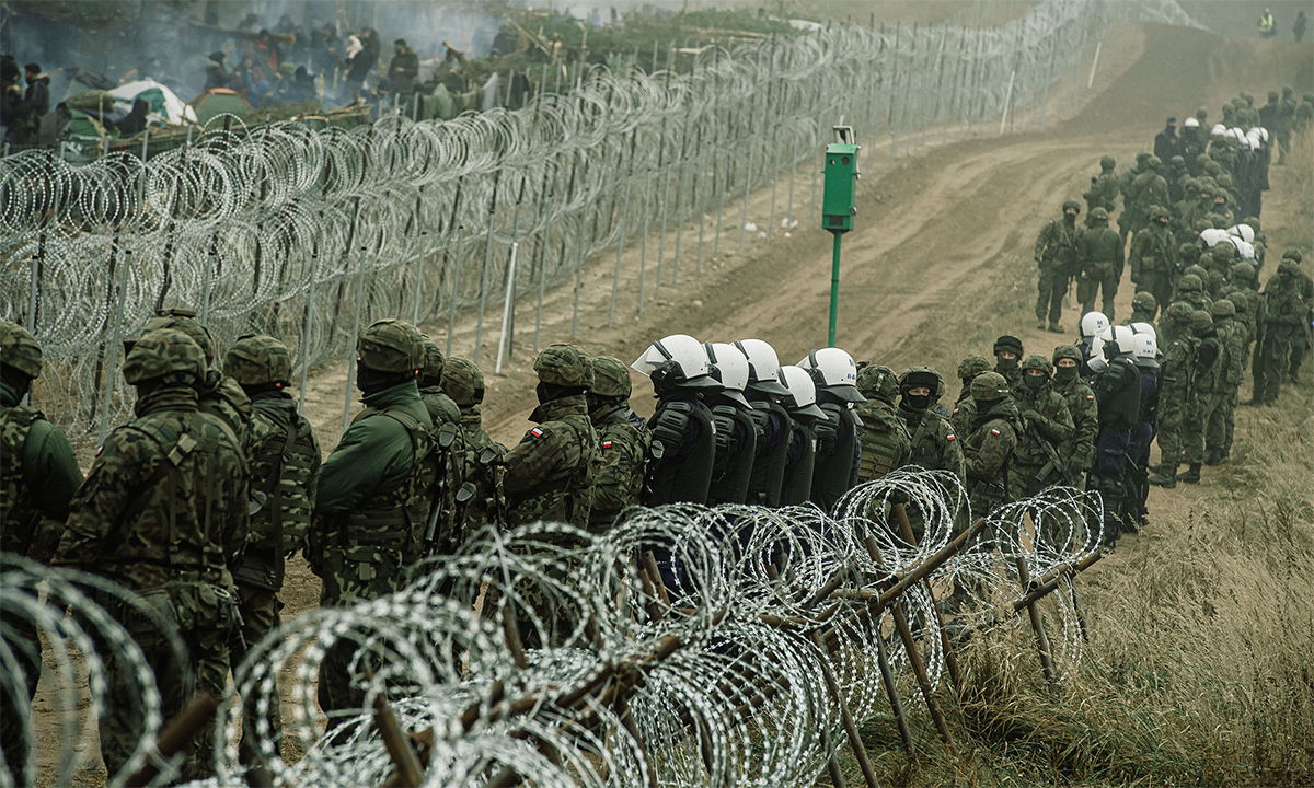 Cảnh sát và binh sĩ Ba Lan dàn quân giám sát người di cư ở biên giới với Belarus đoạn gần làng Kuznica tháng 11/2021. Ảnh: Reuters