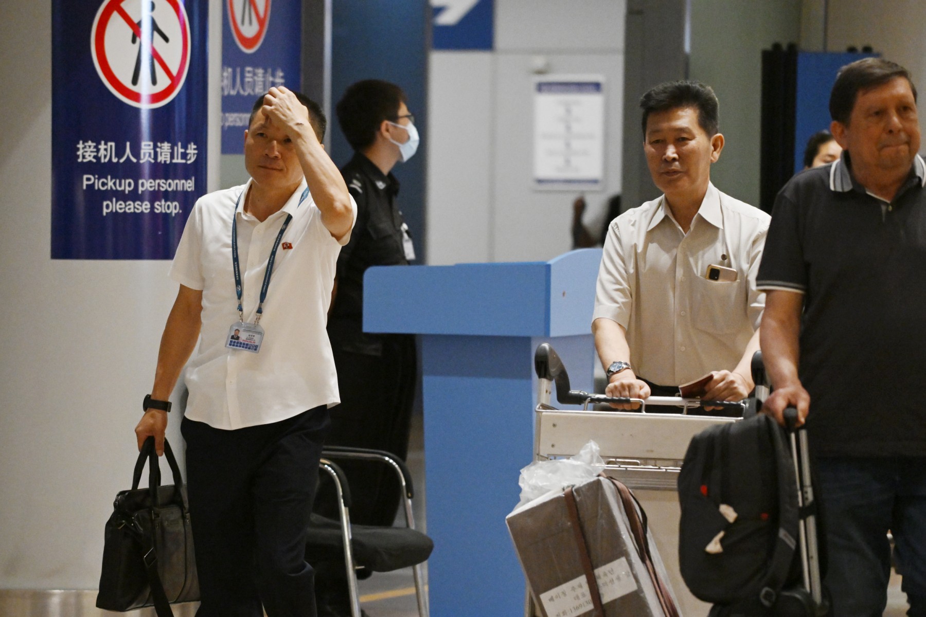 Two North Korean men (L and 2nd R) walk through the arrivals section at Beijing Capital Airport after the arrival of Air Koryo flight JS151 on August 22, 2023.