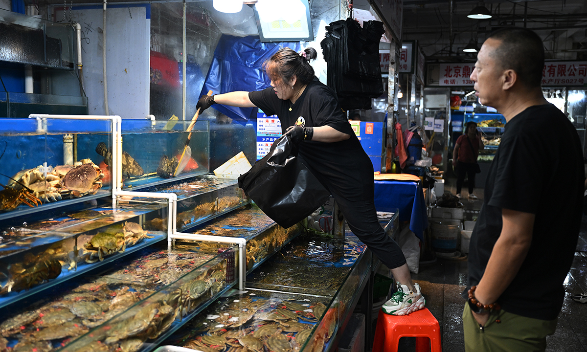 Tiểu thương Trung Quốc lấy hàng cho khách tại một chợ hải sản ở thủ đô Bắc Kinh ngày 24/8. Ảnh: AFP