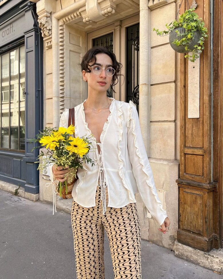 Sơ mi trắng nhún bèo dọc thân và hai tay áo mang đến cảm giác nhẹ nhàng và bay bổng, đậm chất lãng mạn của người phụ nữ Pháp.