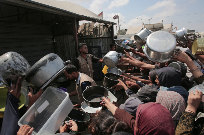 Người dân Palestine giơ những chiếc nồi rỗng trước một bếp ăn từ thiện ở Khan Yunis, phía nam Dải Gaza ngày 21/8. Ảnh: AFP