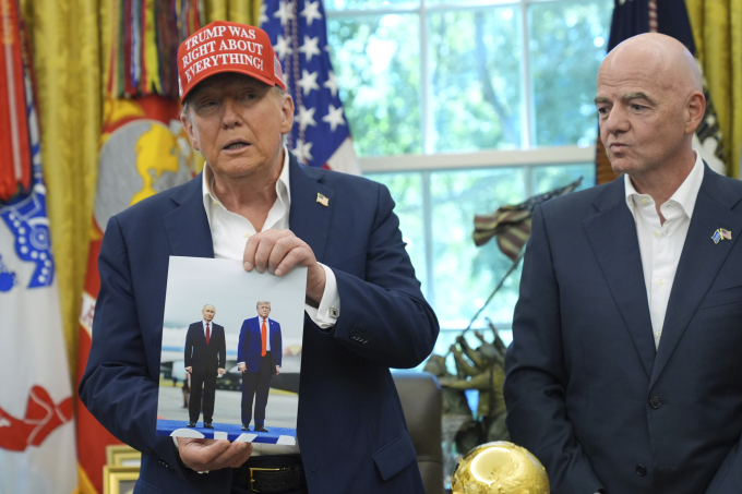 Tổng thống Trump giơ bức ảnh chụp cùng người đồng cấp Nga Putin. Ảnh: AP