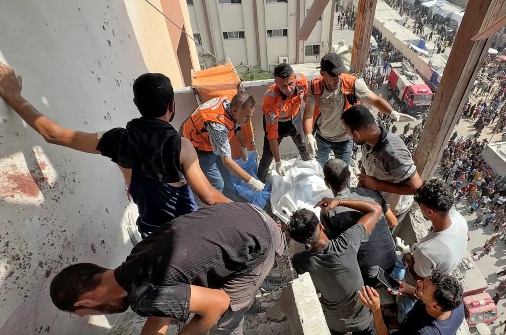 Nhân viên y tế thu dọn thi thể của Hussam Al-Masri tại hành lang bệnh viện Nasser, vài giây trước khi trúng quả đạn pháo thứ hai. Ảnh: Reuters