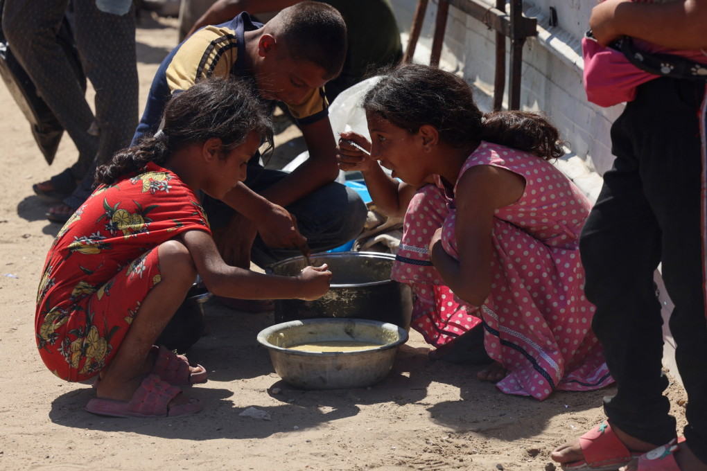 Trẻ em Gaza ăn bữa cơm nhận được từ bếp ăn từ thiện ở Khan Younis ngày 27/8. Ảnh: AFP