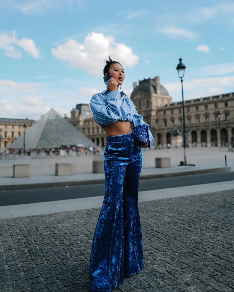 Fashionista Quỳnh Anh Shyn lại lựa chọn cách tiếp cận khác khi đưa sơ mi vào công thức mang cảm hứng thời trang thập niên 1970. Cô phối sơ mi dáng ngắn cùng quần nhung ống loe, tạo nên tổng thể đậm chất retro. Cách kết hợp này cho thấy chỉ cần thay đổi phom áo và lựa chọn một món đồ mang tinh thần đặc trưng của một thời kỳ, sơ mi cơ bản cũng có thể trở thành điểm nhấn cho cả bộ trang phục.