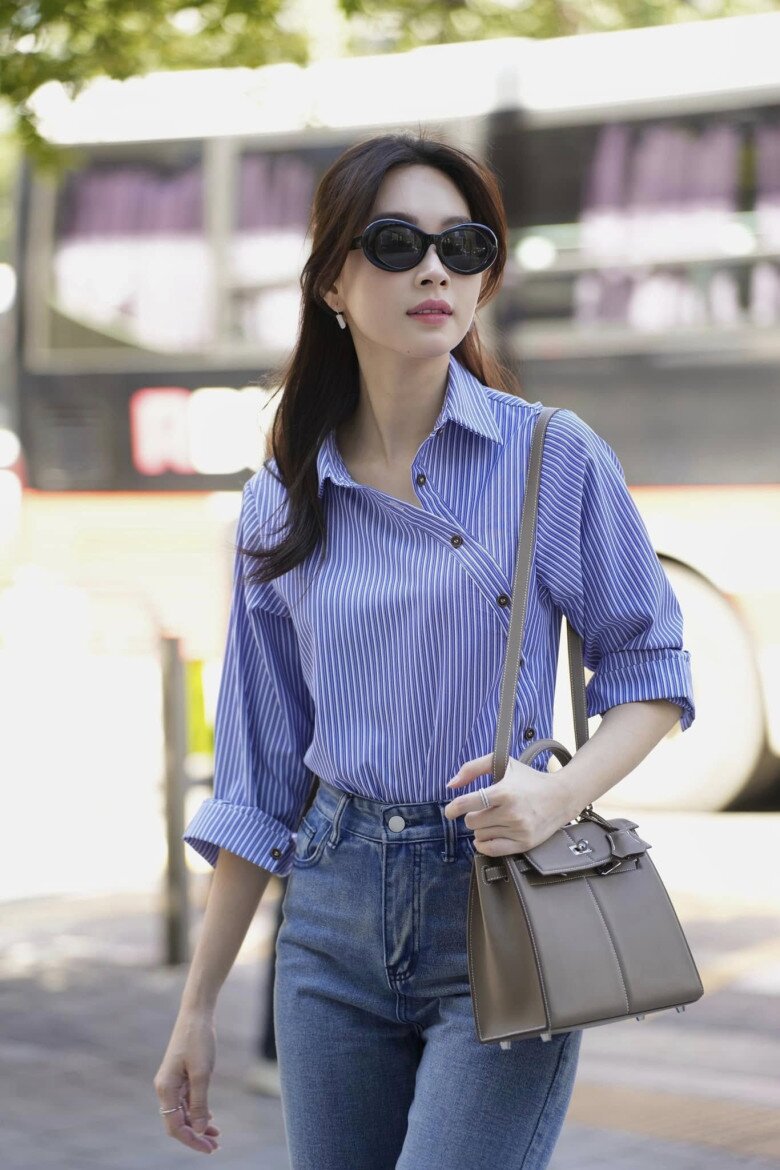 Ở một lần khác, người đẹp làm mới phong cách đường phố với sơ mi kẻ sọc xanh - trắng có phần vạt chéo. Thiết kế phá cách giúp bộ trang phục có thêm nét cá tính mà không cần sử dụng quá nhiều phụ kiện.