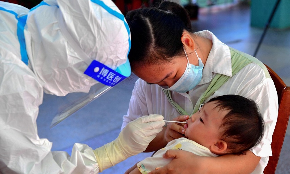 Nhân viên y tế lấy mẫu xét nghiệm Covid-19 cho một em bé ở quận Tiên Du, thành phố Phủ Điền, tỉnh Phúc Kiến hôm 13/9. Ảnh: AFP.