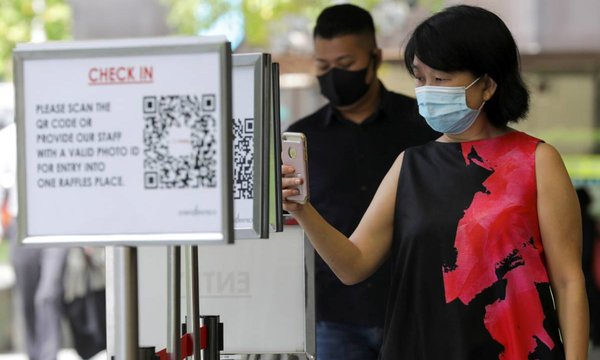 Một người phụ nữ quét mã QR trước khi vào trung tâm mua sắm ở Singapore hồi tháng 5. Ảnh: Reuters.