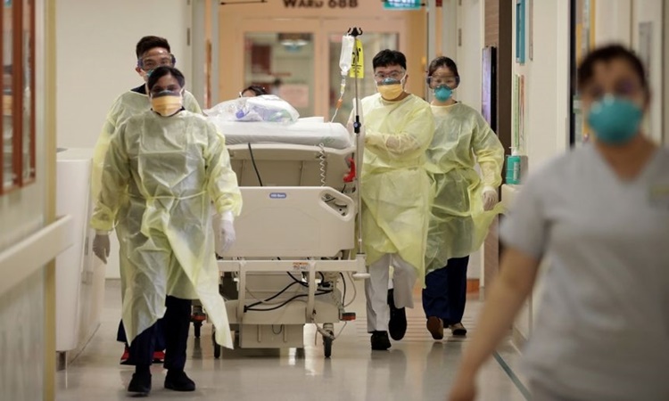 Nhân viên y tế tại Bệnh viện Đa khoa Singapore di chuyển một bệnh nhân Covid-19 tới khu điều trị cách ly hồi năm ngoái. Ảnh: Straits Times.