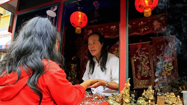 Một phụ nữ đang được đọc chỉ tay tại một tiệm xem bói bên đường ở Singapore, tháng 8/2022. Ảnh: CNBC