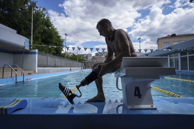 Pavlo Tovstyk tháo chân giả tại bể bơi ở Kiev ngày 12/8, khi đang luyện tập cho cuộc thi bơi vượt biển. Ảnh: AP