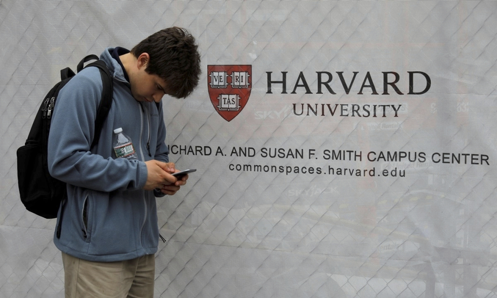 Một sinh viên đứng cạnh banner của Đại học Harvard ở Cambridge, Massachusetts, tháng 6/2018. Ảnh: Reuters