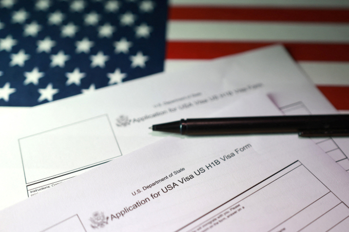 Illustration shows U.S. flag and U.S. H-1B Visa application forms